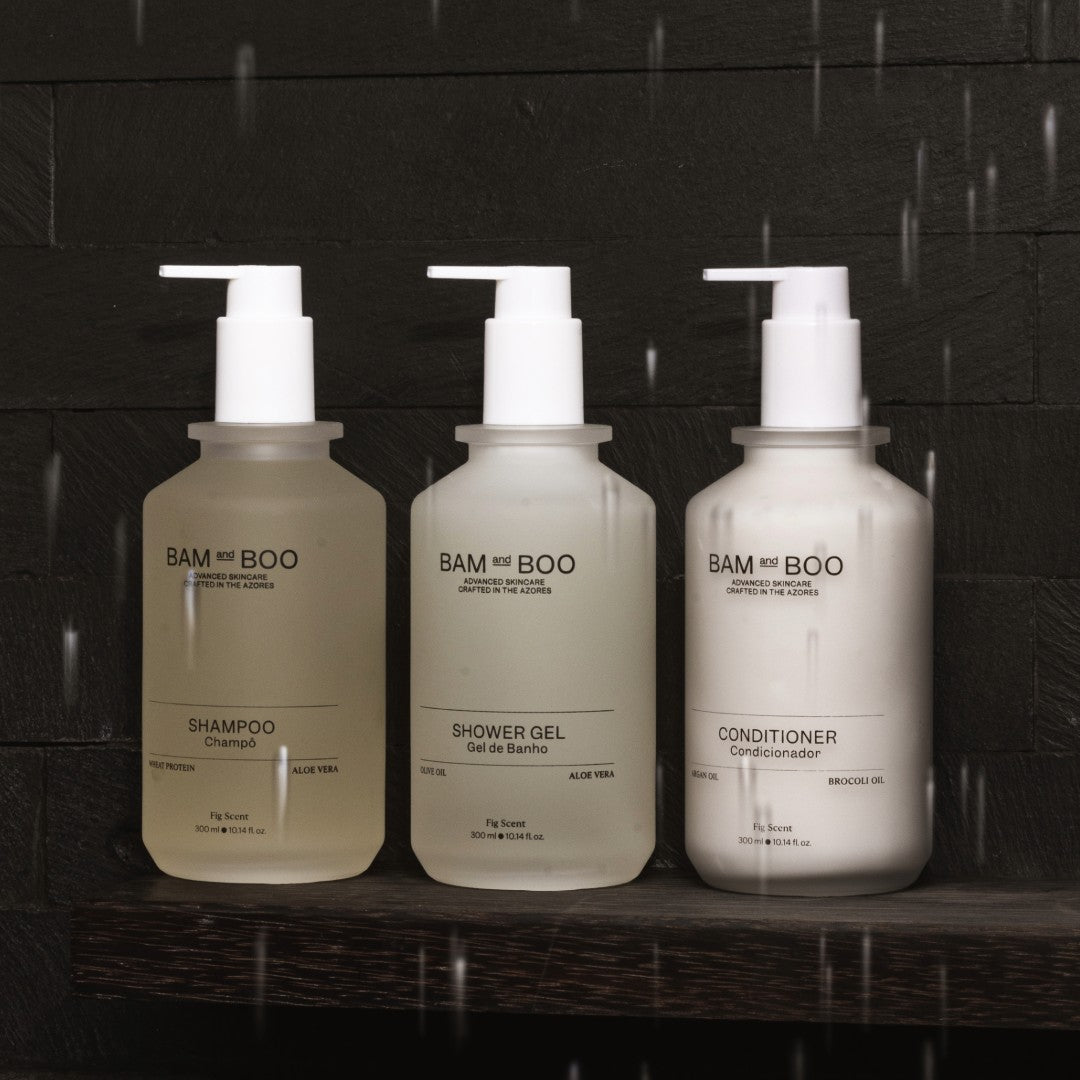 Three bottles of BAM BOO shampoo, shower gel, and conditioner on a dark background. Portuguese hotel amenities.