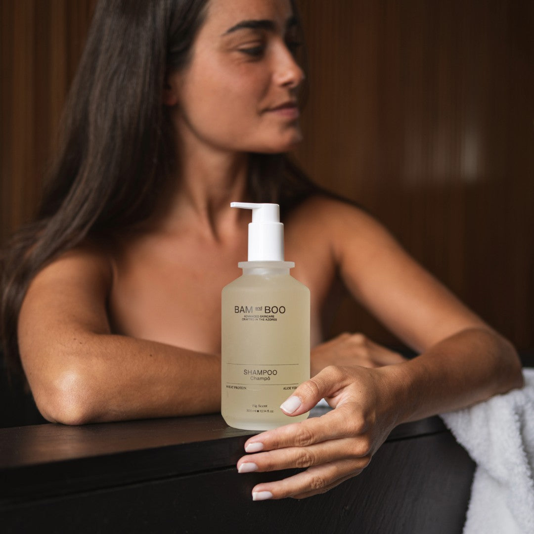 Woman holding a bottle of BAM&BOO shampoo with a blurred background. The best natural amenities made in portugal.